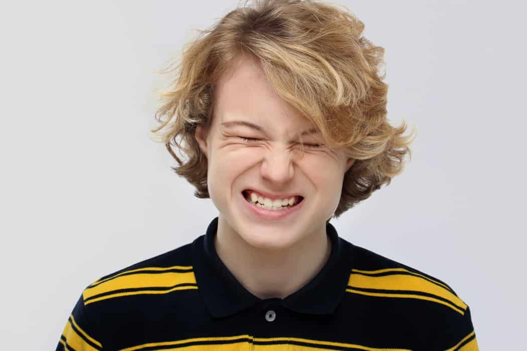 Young person squinting and clenching teeth.